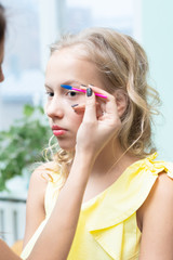 Fototapeta na wymiar Makeup artist paints eyebrows to teen blonde girl