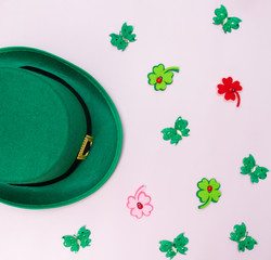 March 17 is the feast of St. Patrick. Green felt hat and shiny paper clover leaves on a white...
