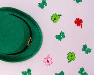 March 17 is the feast of St. Patrick. Green felt hat and shiny paper clover leaves on a white...
