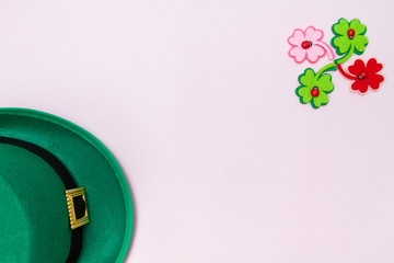 March 17 is the feast of St. Patrick. Green felt hat and shiny paper clover leaves on a white...