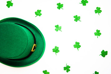 March 17 is the feast of St. Patrick. Green felt hat and shiny paper clover leaves on a white...