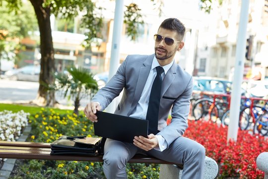 Businessman working with laptop on bench outdoor