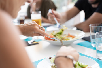 detail of a young blonde girl's hand with a ring cutting food from a plate