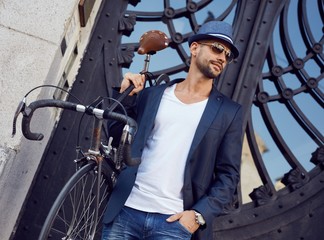 Urban hipster guy in hat with bicycle in city