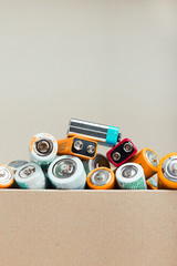 Discharged batteries in cardboard box. Collecting used batteries to recycle. Waste disposal and...
