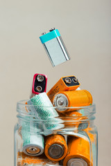 Used battery falling into a jar filled with discharged batteries. Waste disposal and recycling....