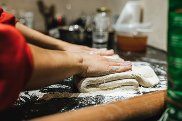 Woman kneading dough on table sprinkled with flour