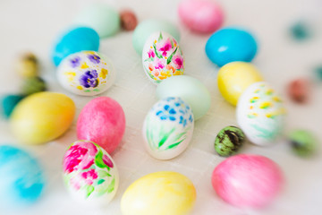 Colorful hand painted with watercolor easter eggs with painting of flowers on lace tablecloth