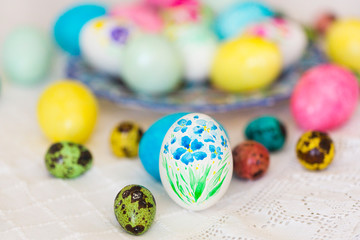 Colorful hand painted with watercolor easter eggs with painting of flowers on lace tablecloth