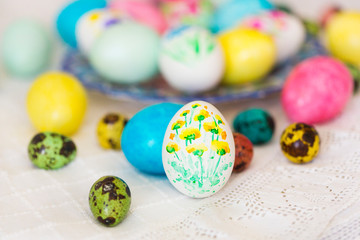 Colorful hand painted with watercolor easter eggs with painting of flowers on lace tablecloth