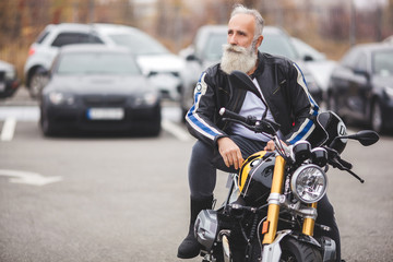Fototapeta na wymiar Mature man riding a motorcycle. Old male on motorbike. Bearded man outdoors driving.