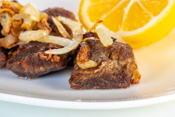 Roast beef with onion and lemon on a white plate.