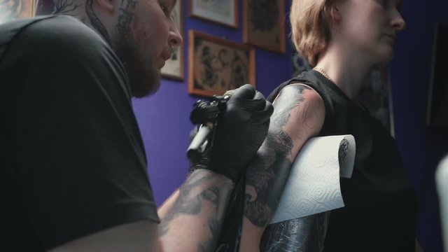 Video of man doing tattoo of snake for woman in studio