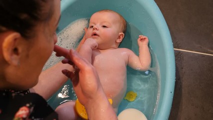 4K: Newborn Baby having a bath in the tub with her mum helping. 
