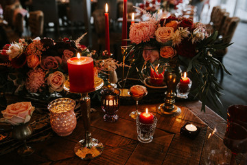 Romantic red table, decorated table with flowers and red candles. Luxury Christmas evening or wedding party decoration.