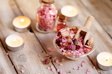 Concept of spa treatment with roses. Crystals of sea pink bath salt, candles as decor. Atmosphere of relax and pleasure. Anti-stress and detox procedure. Luxury lifestyle. Wooden background