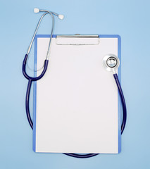 Flat lay of stethoscope and writing pad paper clip board on light blue background with copy space, healthcare and medical concept, top view photo.