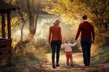 Mother father and daughter are walking along the forest path three and around the trees with yellow...