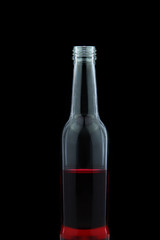 Glass bottle with red water inside on black background.
