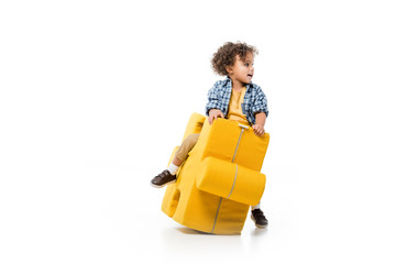 happy african american boy sitting on yellow puzzle chair, isolated on white