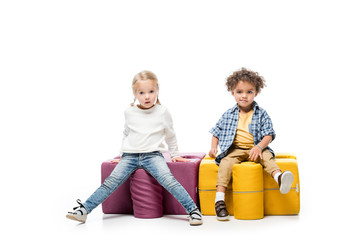 funny multicultural kids sitting on puzzle chairs, on white