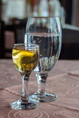 Still life with a glass of grape brandy, and a glass of sparkling water on a table.