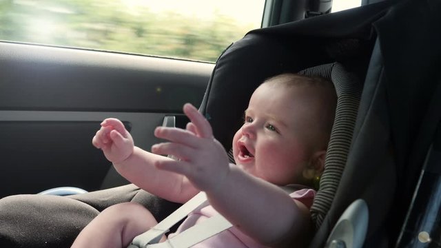 4K: Baby travelling in a Car seat in the back of a vehicle. This child is safely strapped in with a seatbelt on. Slow motion