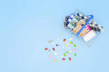Buy and shopping medicine concept. Various capsules, tablets and medicine in shop basket on a blue background. Creative idea for health care and pharmaceutical company. Copy space and top view.