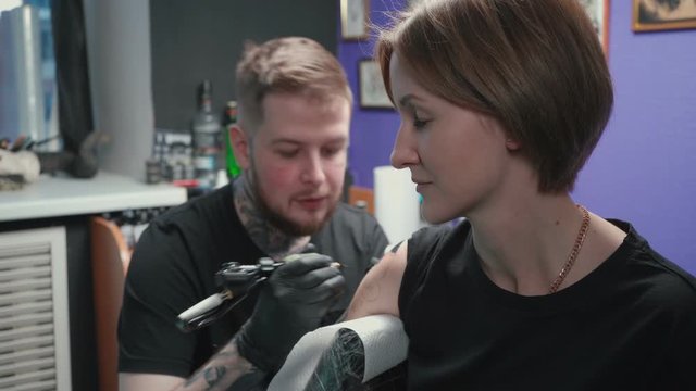 Video of man doing black tattoo for woman in studio