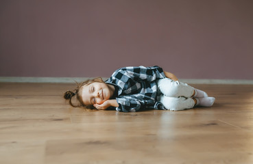 Funny portrait of lying sleep little girl on a floor indoors
