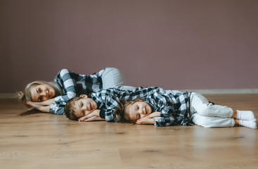 Top view of mother and her two kids in identical clothes lying on floor with closed eyes.