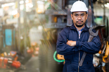 Portrait of Asian mechanic Fold over holding a wrench and smiling at truck and forklift garage. Industrial mechanic Engineer in Hard Hat