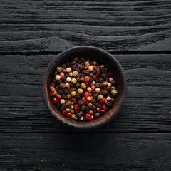 Peppers in a bowl on a black wooden background. Top view. Free space for your text.
