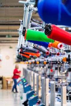 Colorful reel thread set up at modern and automatic sewing or embroidery spinning machine, textile industry factory concept