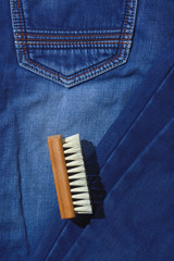 a clothes brush lies on folded jeans.