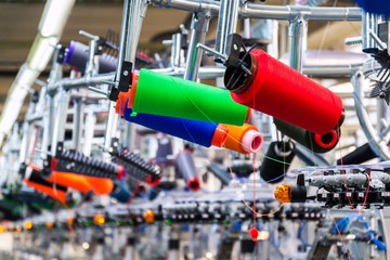 Colorful reel thread set up at modern and automatic sewing or embroidery spinning machine, textile industry factory concept - obrazy, fototapety, plakaty