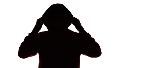 dark male silhouette in casual sportswear with a hood, figure of a guy hiding his face, concept of privacy and confidentiality