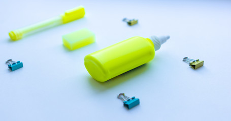 Mixed stationery in yellow and blue colours: clips, eraser, glue and marker pen on white background. Concept of education, business, minimalism. Selective focus.