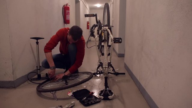 A man disassembles a bicycle wheel in a garage.