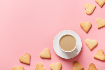Cup of coffee and cookies shaped of heart on pink. Valentine card. Flat lay, copy space.
