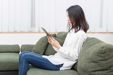 Obraz premium リビングでタブレットを操作する女性