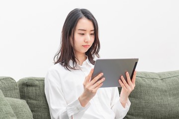 リビングでタブレットを操作する女性