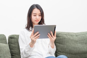 Fototapeta premium リビングでタブレットを操作する女性