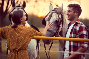 Happy couple having fun on the horse ranch. Fun on countryside, sunset golden hour. Freedom nature...