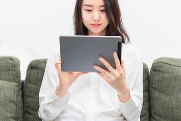 Fototapeta premium リビングでタブレットを操作する女性