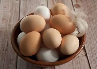 Easter composition. Fresh farm chicken eggs in a clay Cup close-up on a wooden background. Selective focus.