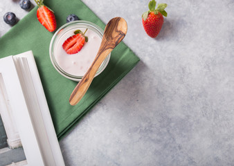 Organic probiotic milk kefir drink or yogurt in glass with strawberry, on the white grey background. Gut health. Fermented dairy beverage. Trendy food. Copy space