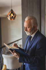 Fototapeta premium Senior businessman writing in a planner