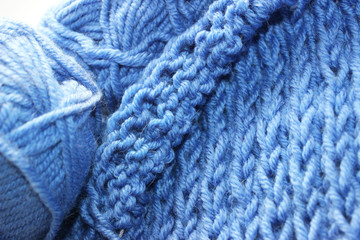 A piece of blue knitting with balls of yarn and knitting needles. Knitted woolen yarn fabric. Knitting project in progress concept.  © Sunbunny