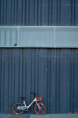 grey bicycle, orange wheels parked on the wall.Vehicles with 2 wheels, driving with manpower.